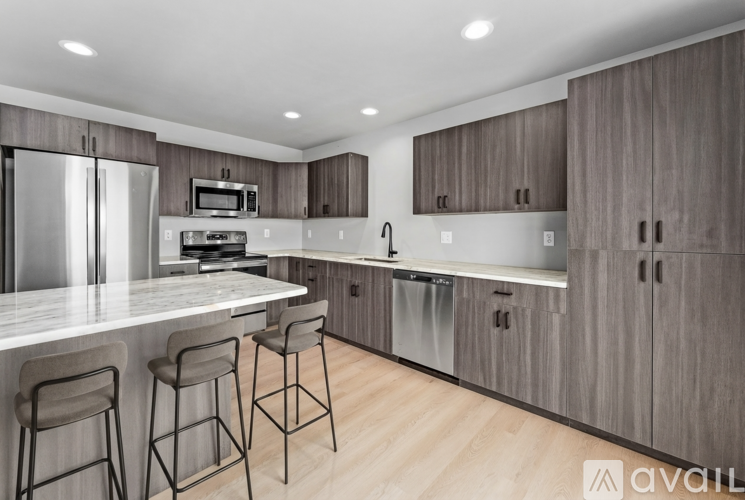 A modern kitchen with wooden cabinets and a marble countertop.