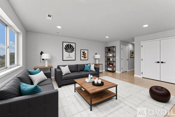 A modern living room with a grey sofa, a wooden coffee table, and a large window.