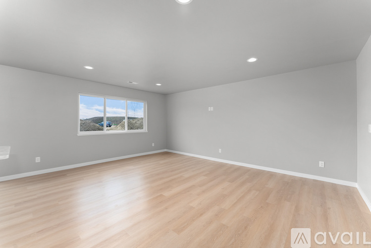 A spacious room with wooden flooring and a large window.