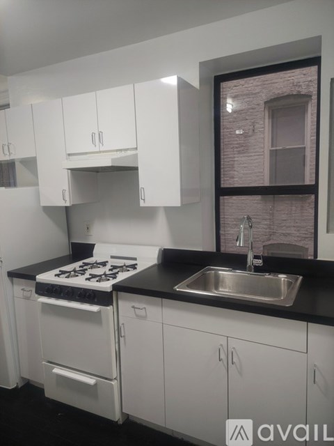 A kitchen with white cabinets and a black countertop.