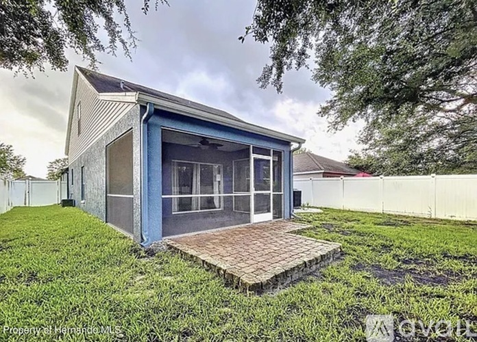A blue house with a white fence and a brick walkway leading to the front door.
