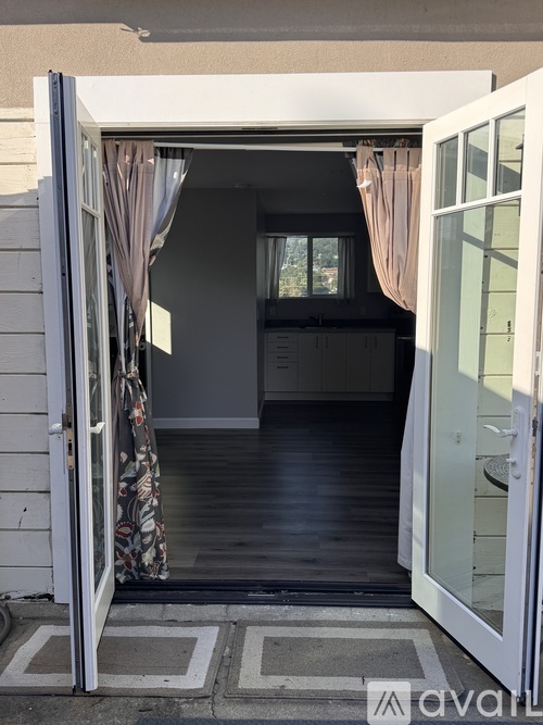 A white door with a glass window and curtains is open.