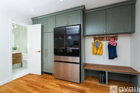 A kitchen with green cabinets and a stainless steel refrigerator.