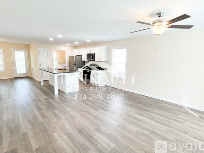 A spacious living room with a ceiling fan and hardwood flooring.