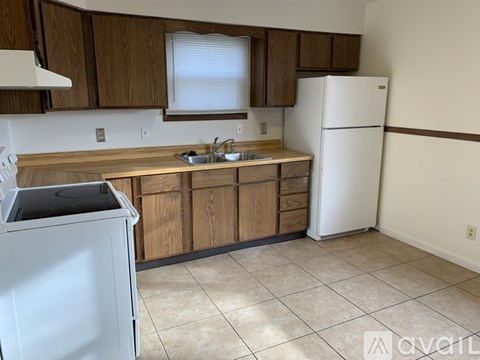 A kitchen with a white refrigerator, a white dishwasher, and wooden cabinets.