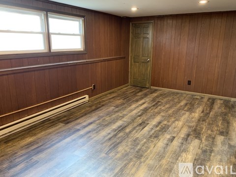 A room with wooden flooring and a wooden door.