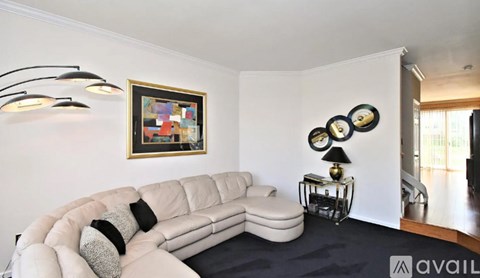 A living room with a white sofa and a painting on the wall.