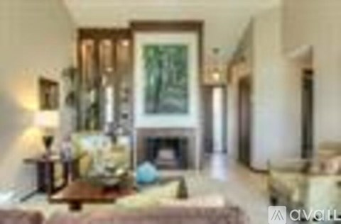 A living room with a fireplace and a painting on the wall.