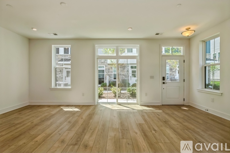 A spacious room with wooden floors and a large window overlooking a building.