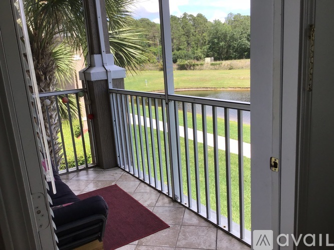 A balcony with a chair and a view of a grassy area.