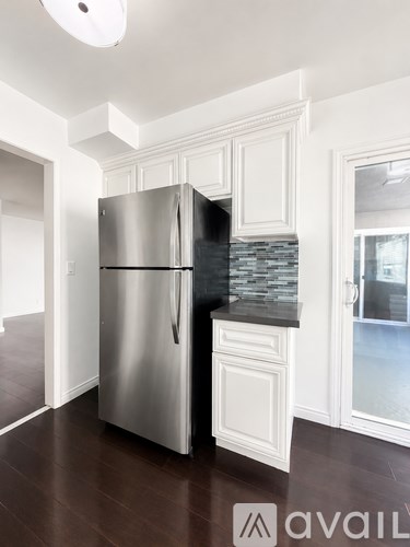 A stainless steel refrigerator in a kitchen with white cabinets.