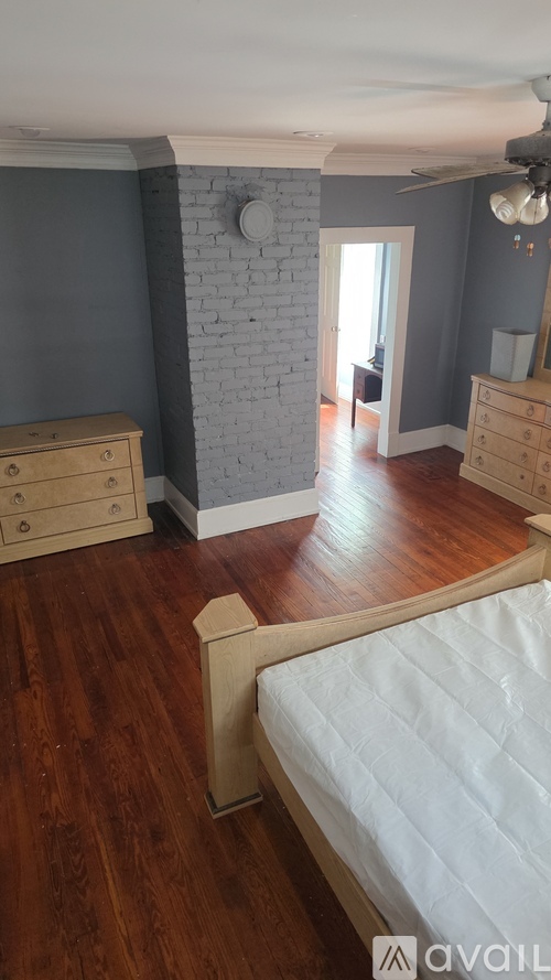 A bedroom with a bed, dresser, and a ceiling fan.