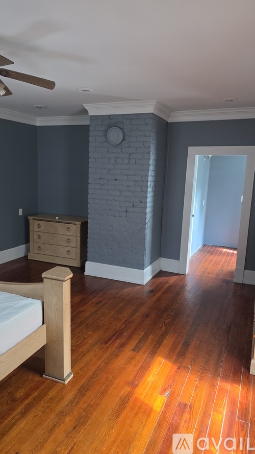 A bedroom with a bed, dresser, and wooden floors.