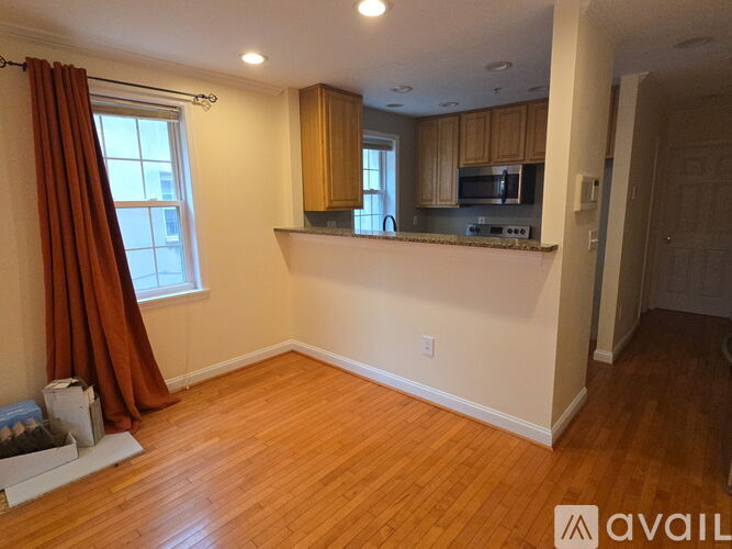 A room with wooden floors and a window with curtains.