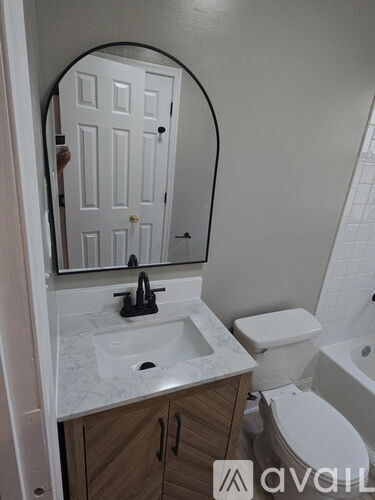 A bathroom with a sink, toilet and mirror.