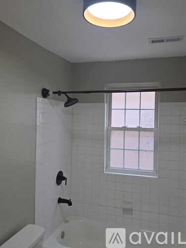 A bathroom with a white tub and a window.