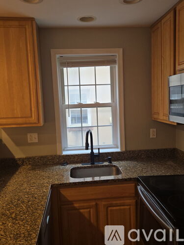 A kitchen with a granite countertop and wooden cabinets.