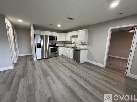 A kitchen with white cabinets and a wooden floor.