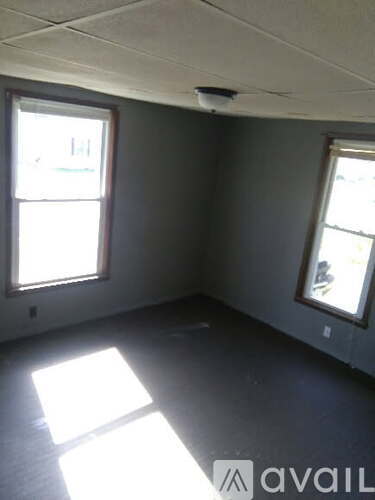 A room with two windows and a ceiling fan.
