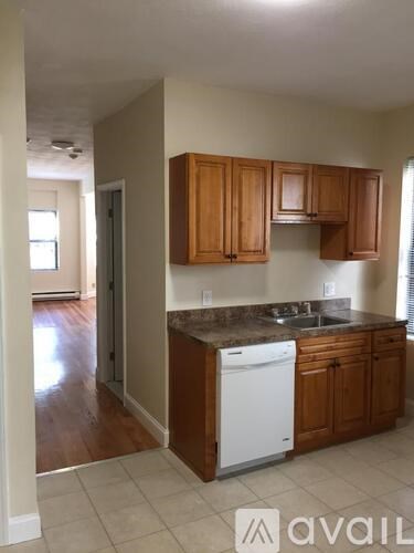 A kitchen with wooden cabinets and a white dishwasher.