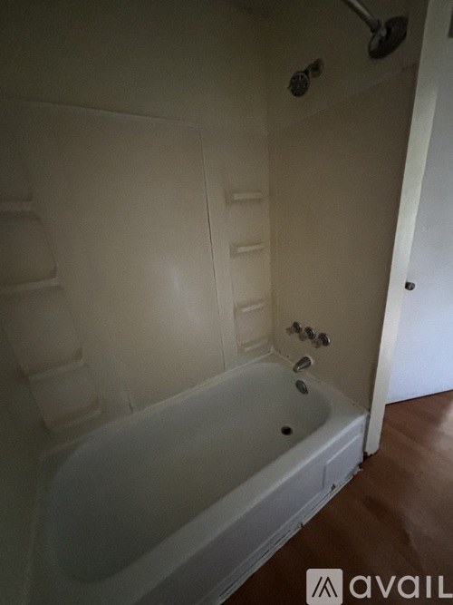 A white bathtub with a shower head and faucet.