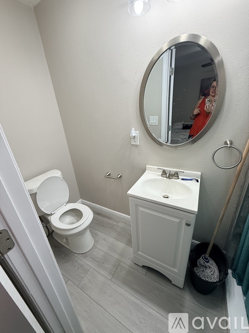 A bathroom with a toilet, sink, and mirror.