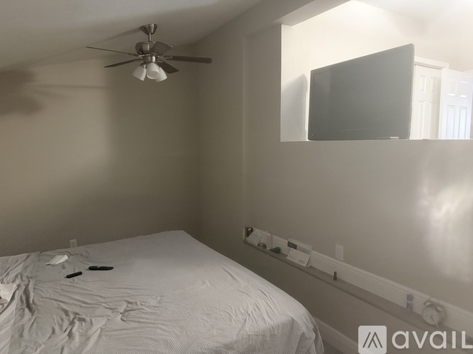 A bedroom with a bed, a ceiling fan, and a mirror on the wall.