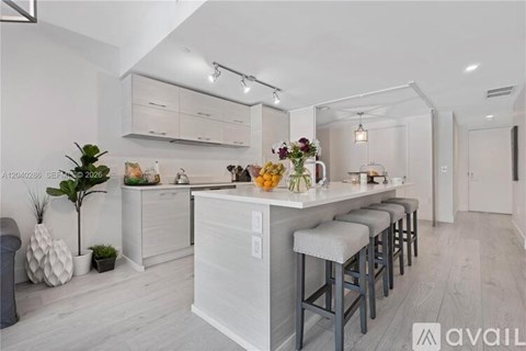 A kitchen with white cabinets and a bar area with stools.