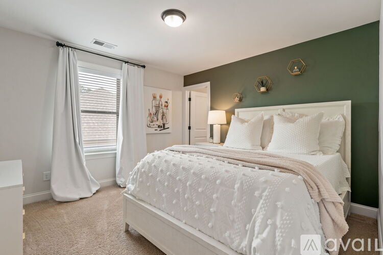 A bedroom with a large bed and a window with curtains.