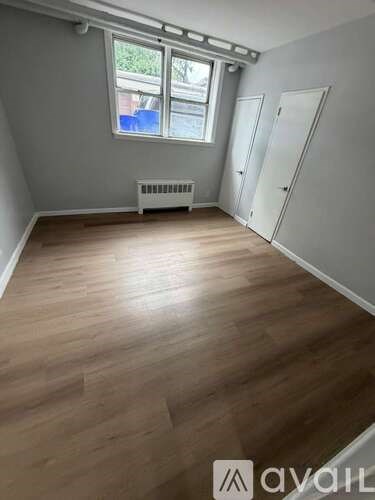 A room with wooden flooring and a window with a view of trees outside.