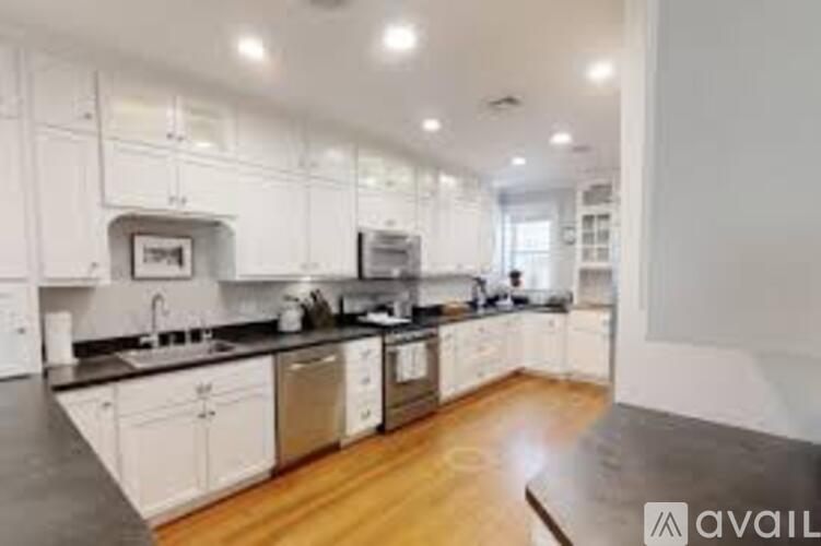 A modern kitchen with white cabinets and black countertops.