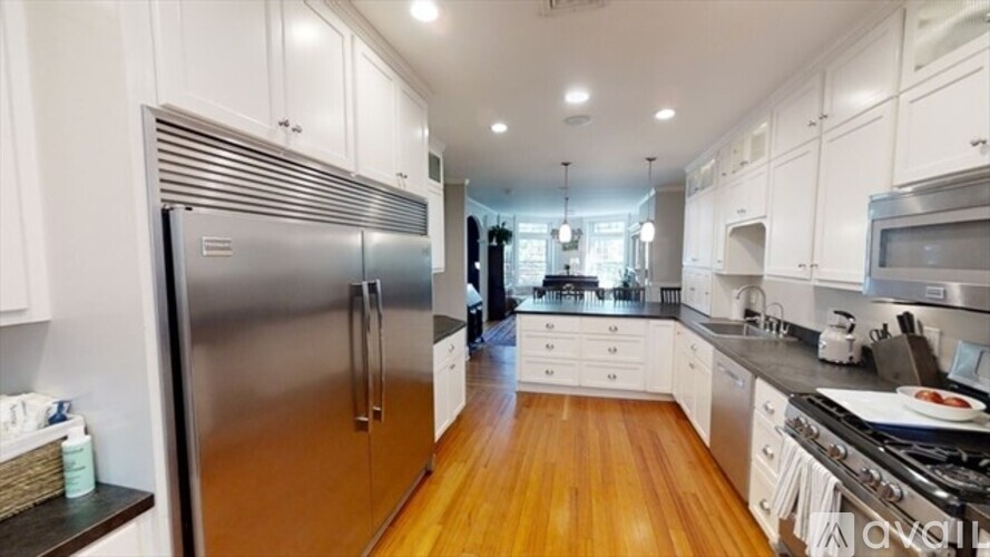 A modern kitchen with a stainless steel refrigerator and wooden floors.