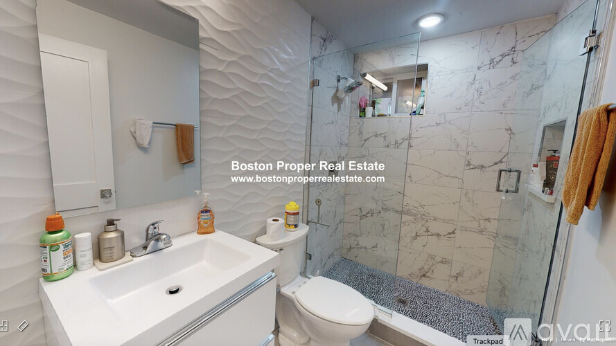 A bathroom with a marble wall and a white sink.