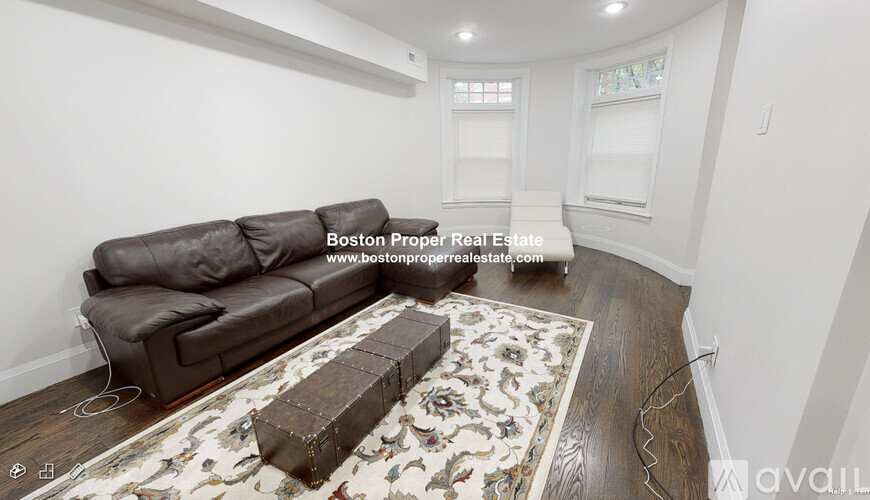 A living room with a brown couch and a floral rug.