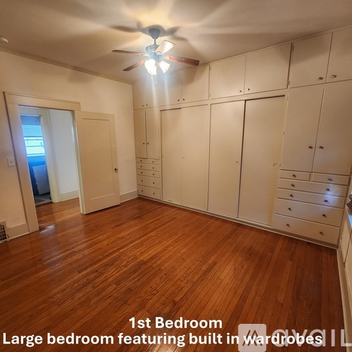 A large bedroom with built-in wardrobes and a ceiling fan.