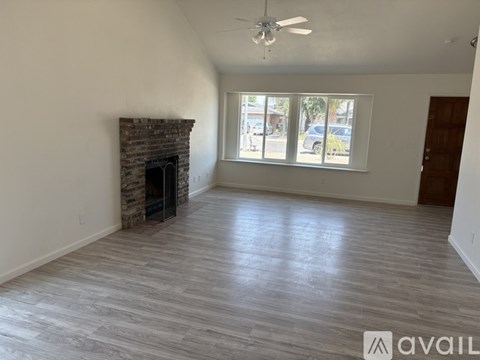 A spacious room with a fireplace and a ceiling fan.