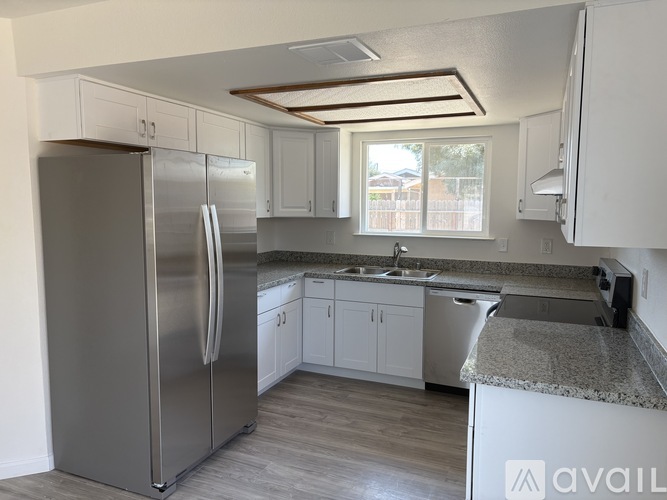 A kitchen with a stainless steel refrigerator and white cabinets.