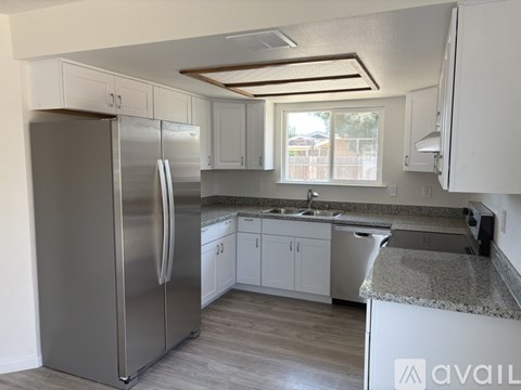 A kitchen with a stainless steel refrigerator and white cabinets.