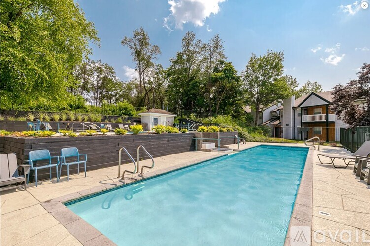 A swimming pool surrounded by a stone wall and lounge chairs.