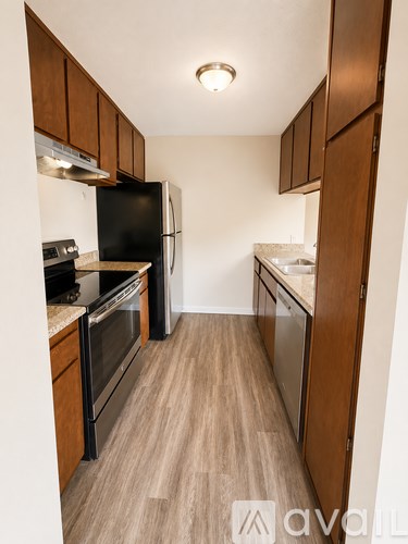 A kitchen with wooden cabinets and a black fridge.
