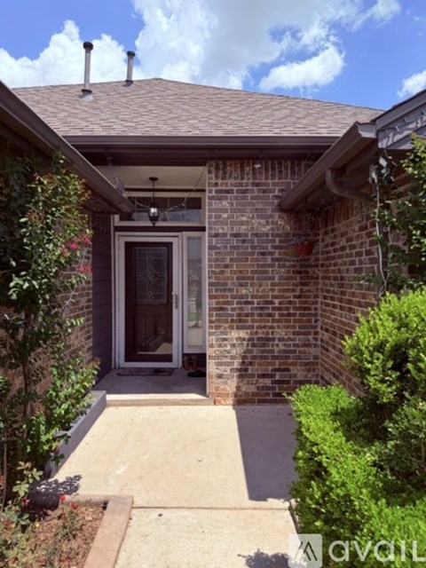 A house with a brown roof and a glass door surrounded by green plants.