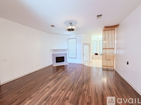 A spacious room with a fireplace and wooden flooring.