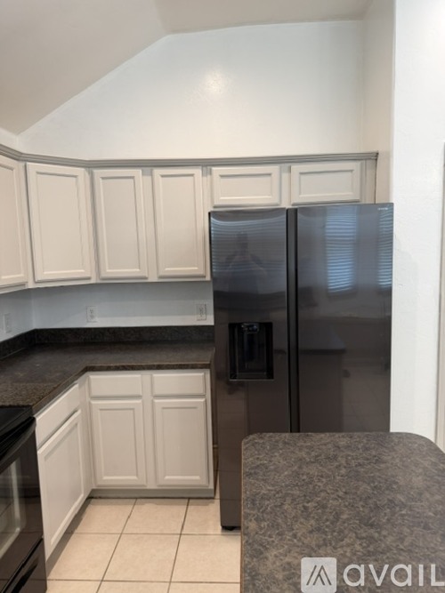 A kitchen with a granite counter top and a refrigerator.