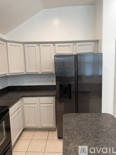 A kitchen with a granite counter top and a refrigerator.
