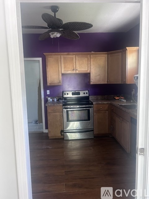 A kitchen with a purple wall and wooden cabinets.