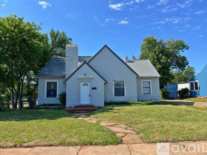 A white house with a grey roof is for sale.