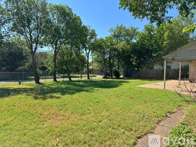A backyard with a fence, trees, and a small building.