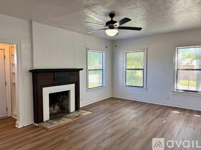 A living room with a fireplace and a ceiling fan.