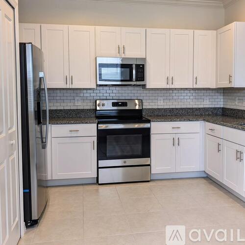 A kitchen with white cabinets and a black refrigerator.
