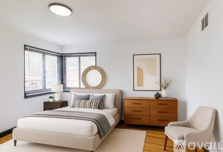 A bedroom with a bed, a chair, and a painting on the wall.